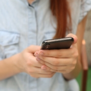 A stock photo of a woman, from the shoulders down, holding a phone in her hands.