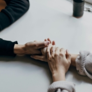 A photo of two people's hands holding each other on a table.