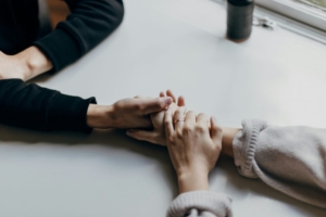 A photo of two people's hands holding each other on a table.