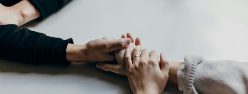 A photo of two people's hands holding each other on a table.