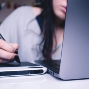 A woman working on a laptop and drawing tablet.