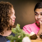 A man and a woman eating and looking at one another.