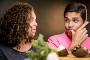 A man and a woman eating and looking at one another.