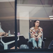 A woman in an office sitting in front of a window looking thoughtful.