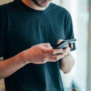 A man from the neck down, typing on a phone.