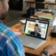 A photo showing a Black man sitting at a table having a video call with a Black woman.