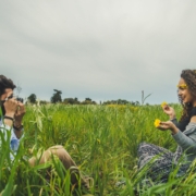 A man and a woman taking pictures in a field with flowers.