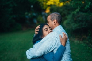 A Black couple hugging outdoors. 