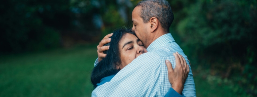 A Black couple hugging outdoors.