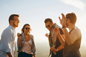 A group of 4 people smiling and standing in a circle outside.