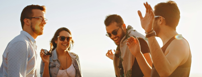 A group of 4 people smiling and standing in a circle outside.