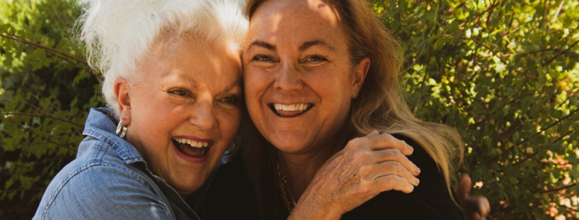 A stock photo of a middle aged white woman and an older white woman embracing outside.