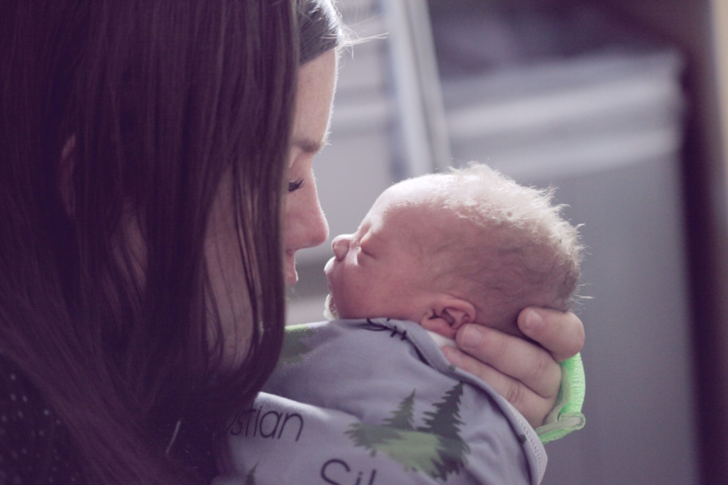 A woman holding a small baby up to her face.