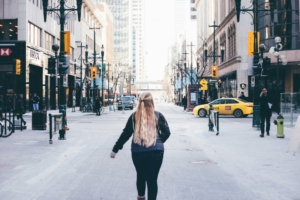 A woman walking down a city street, from behind.