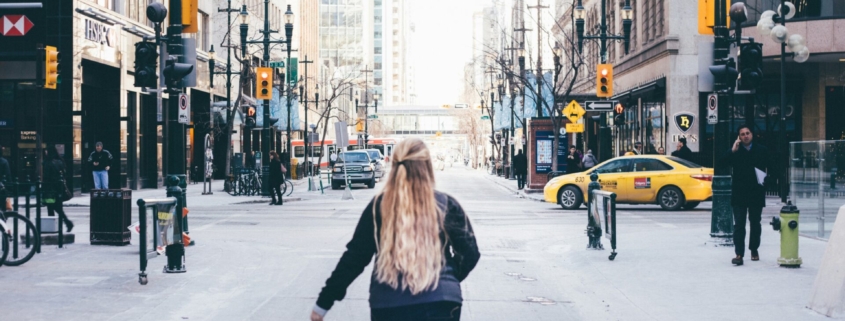 A woman walking down a city street, from behind.