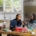 Two women, one of Asian heritage and one Black, sitting together in a kitchen, talking and smiling.