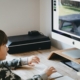 An elementary school age Asian boy sitting at a desk using a desktop computer.