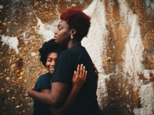 A Black woman embracing a teenage Black girl.