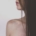 The bare shoulder and lower face of a person with long dark hair.