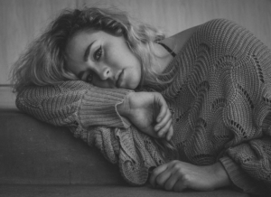 A black and white photo of a white woman laying on her side.