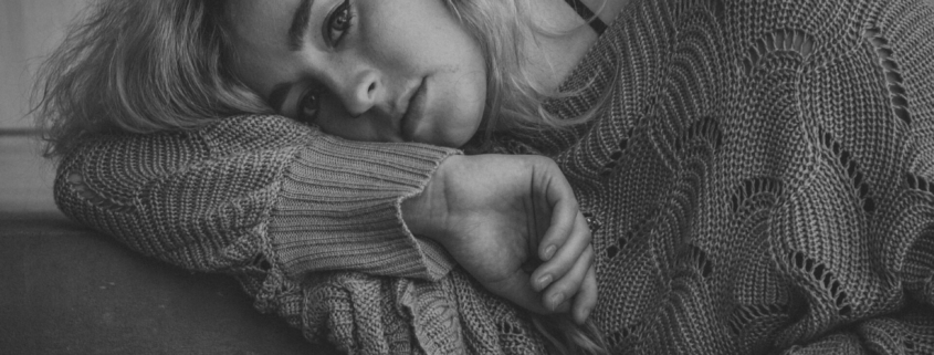 A black and white photo of a white woman laying on her side.