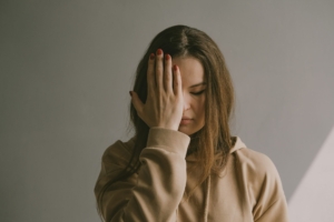 A white woman with her hand on her forehead, looking frustrated.