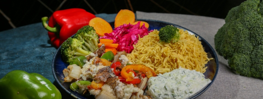 A plate of food including cooked vegetables and rice, with whole vegetables on the table surrounding the plate.