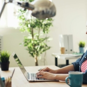 A white woman in an office, working on a laptop.