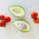 Tomatoes and an avocado on a countertop from above.