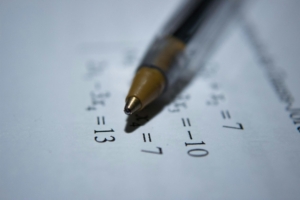 A close up of a math worksheet with a pen laying on top.