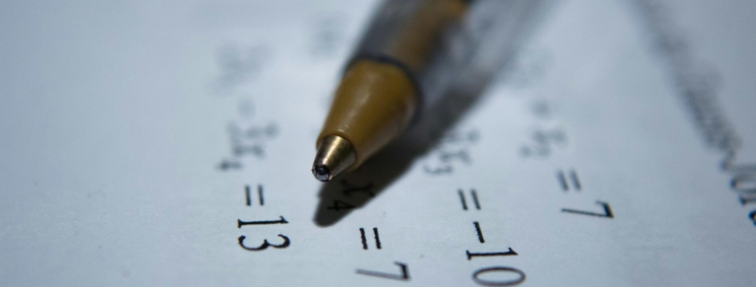 A close up of a math worksheet with a pen laying on top.