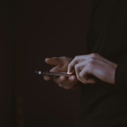 Disembodied hands holding a cell phone against a dark background.