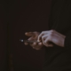 Disembodied hands holding a cell phone against a dark background.