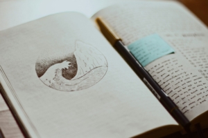 An open journal showing a drawing of a wave on one page and writing on the other.