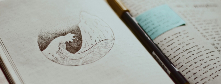 An open journal showing a drawing of a wave on one page and writing on the other.