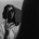 A woman staring through a transparent hexagon at her reflection in the mirror.
