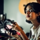 A teenage girl looking at the camera and holding a pair of headphones in her hands.