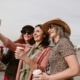 A group of middle aged women taking a selfie outside while holding coffee.