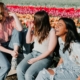A group of women laughing on a bench next to a colorful field of tulips.