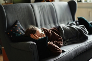 A woman laying on a couch looking sad.