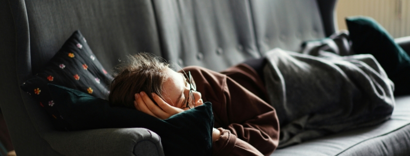 A woman laying on a couch looking sad.