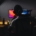A person, from behind, sitting at a computer in a dark room.