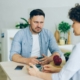 An frowning man sitting at a table across from a woman.
