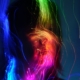 A silhouette of a person with long hair with colorful bands of light over their face.
