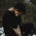 A person sitting outside with their head in their hands, looking upset.
