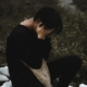 A person sitting outside with their head in their hands, looking upset.