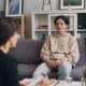 A young person sitting on a couch in a therapist office, with their therapist sitting across from them.