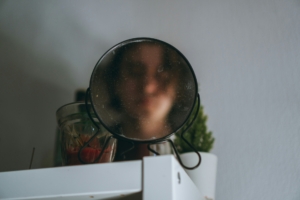 A blurry face in a mirror on top of a cabinet.
