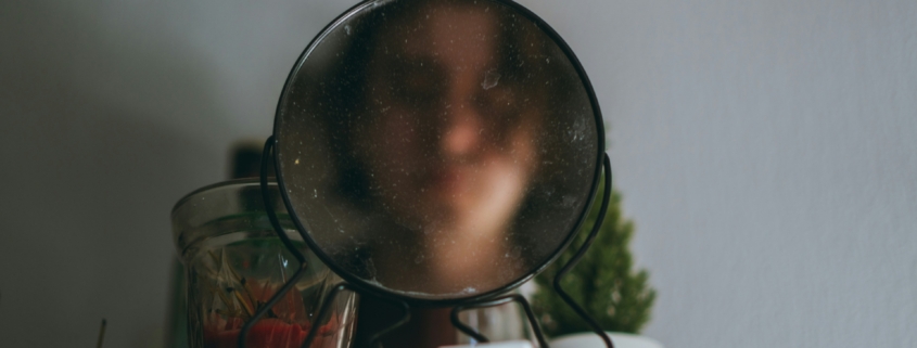 A blurry face in a mirror on top of a cabinet.
