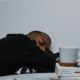 A young man asleep with a book and coffee mug next to him.